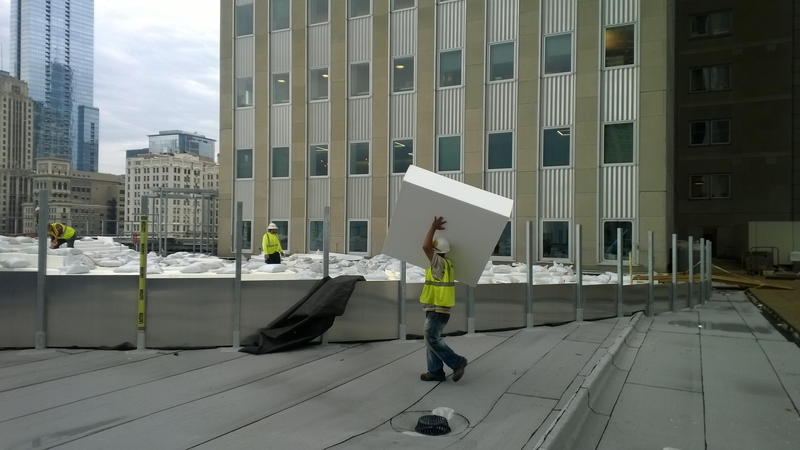 A construction worker carrying an EPS Geofoam block above their head.