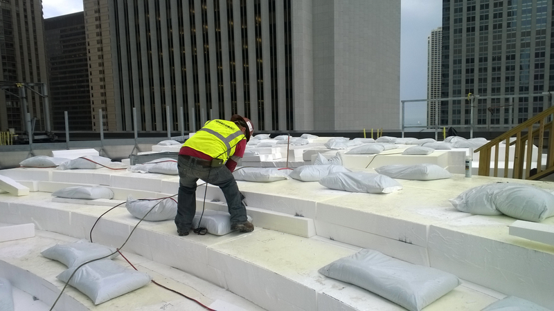 A construction worker installing EPS blocks on a city rooftop.